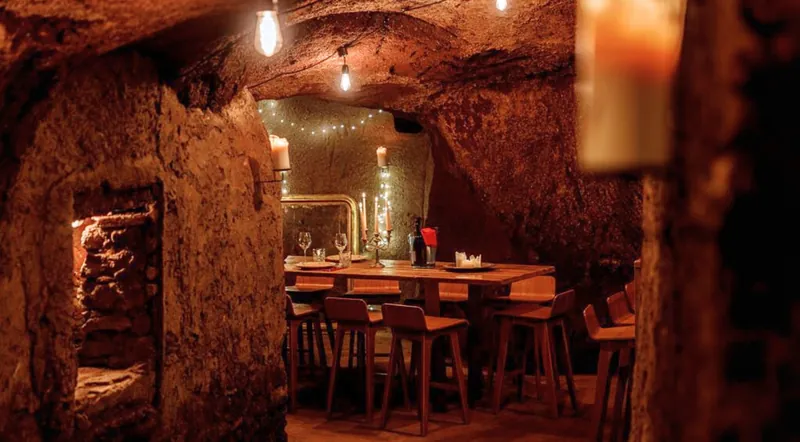 A long table set for dinner inside a carved tufa cave in Rome