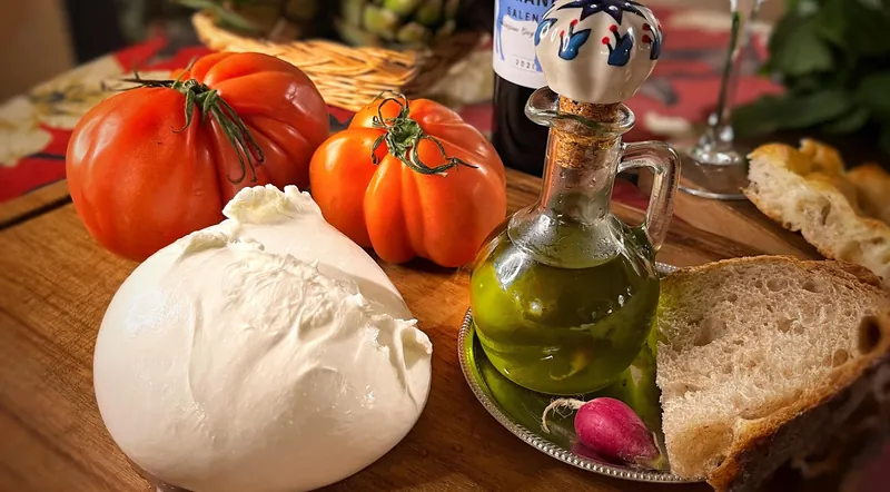 Burrata, ripe tomatoes, olive oil and bread beside a wine bottle