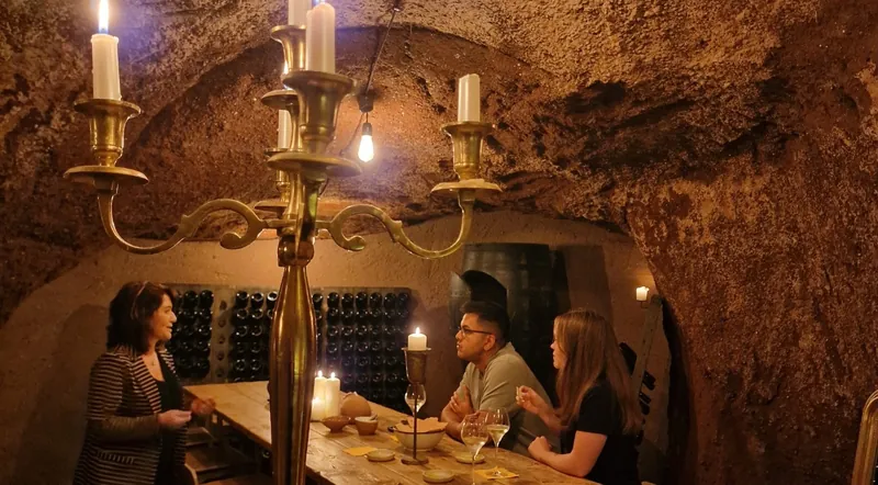 Guests at a candlelit table in an ancient tufa cave used for wine tastings in Rome