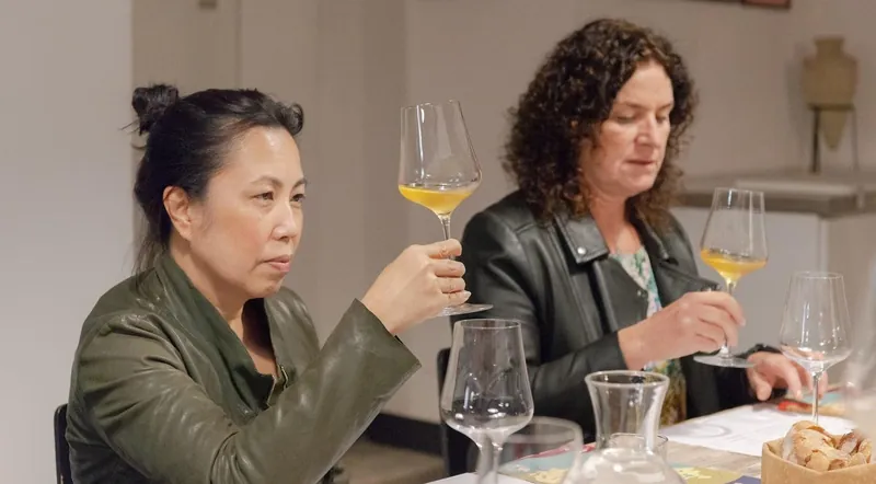 Two guests raising glasses of white wine to the light at a guided tasting in Rome