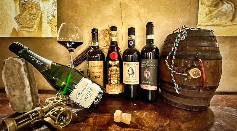 Italian red wine bottles, a prosecco bottle and a small barrel on a cellar table in Rome