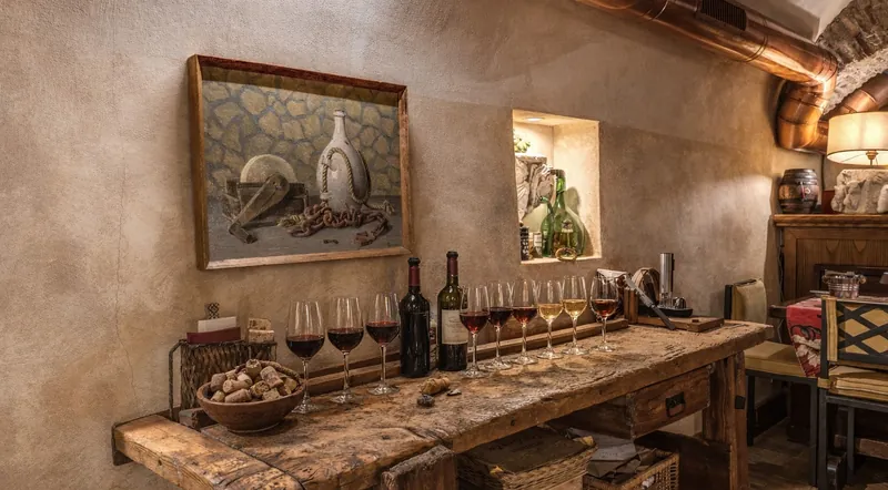 A rustic tasting table with a row of wine glasses in a stone-walled Roman cellar