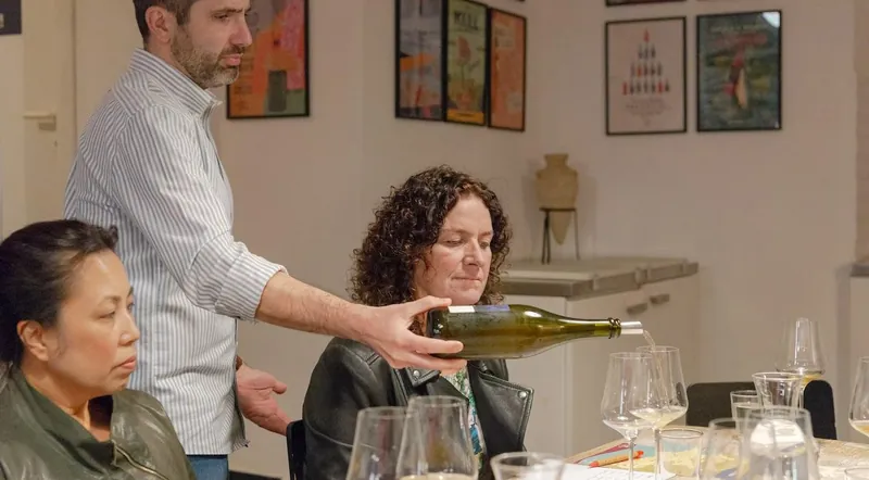 A sommelier pouring white wine for guests at a tasting table in Prati, Rome