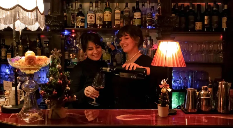 Two hosts pouring wine behind a red-lit speakeasy bar in Monti, Rome