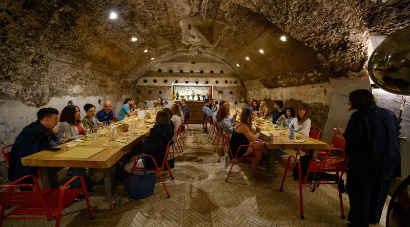 Guests at long tables inside the vaulted tufa wine cave of Taste’Accio in Testaccio
