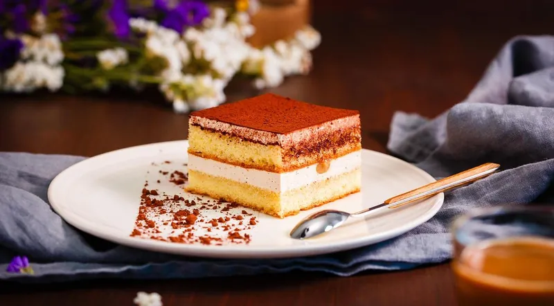 A slice of tiramisu on a plate in a dim restaurant near the Vatican