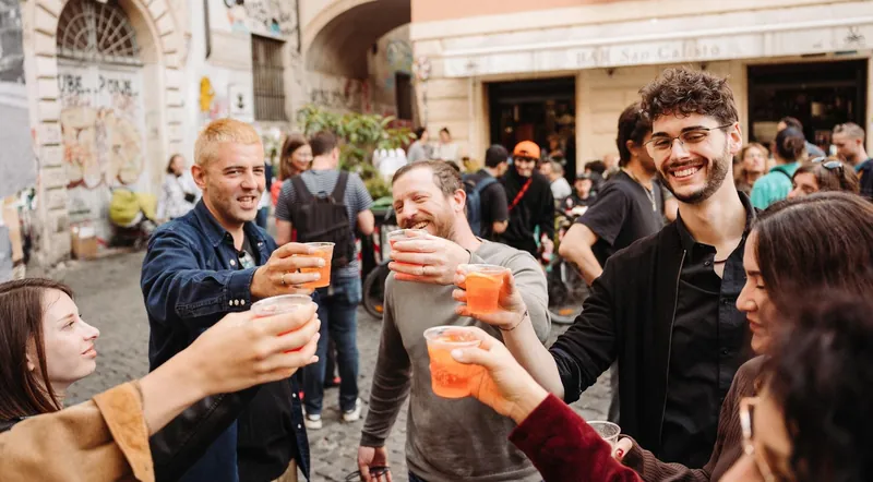 A food tour group toasting with spritz glasses on a Trastevere street