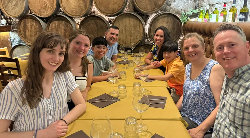 A group at a long tasting table beneath stacked wine barrels in Rome
