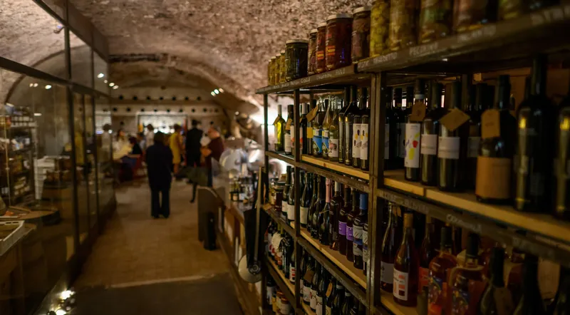 Shelves of wine and preserved goods along the walls of the Testaccio cave