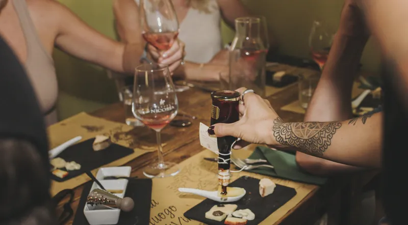 Hands reaching for wine glasses and small plates at a Trastevere food-and-wine pairing