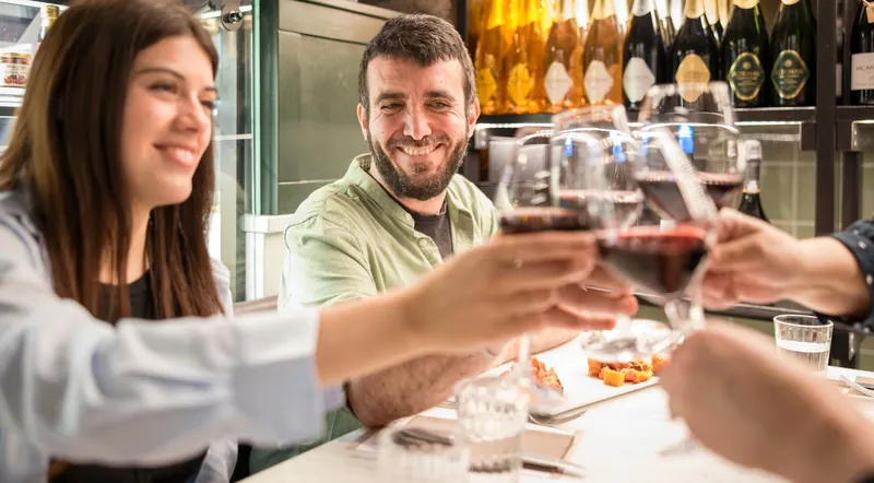 Two guests clinking glasses of red wine at a food tour stop in Rome